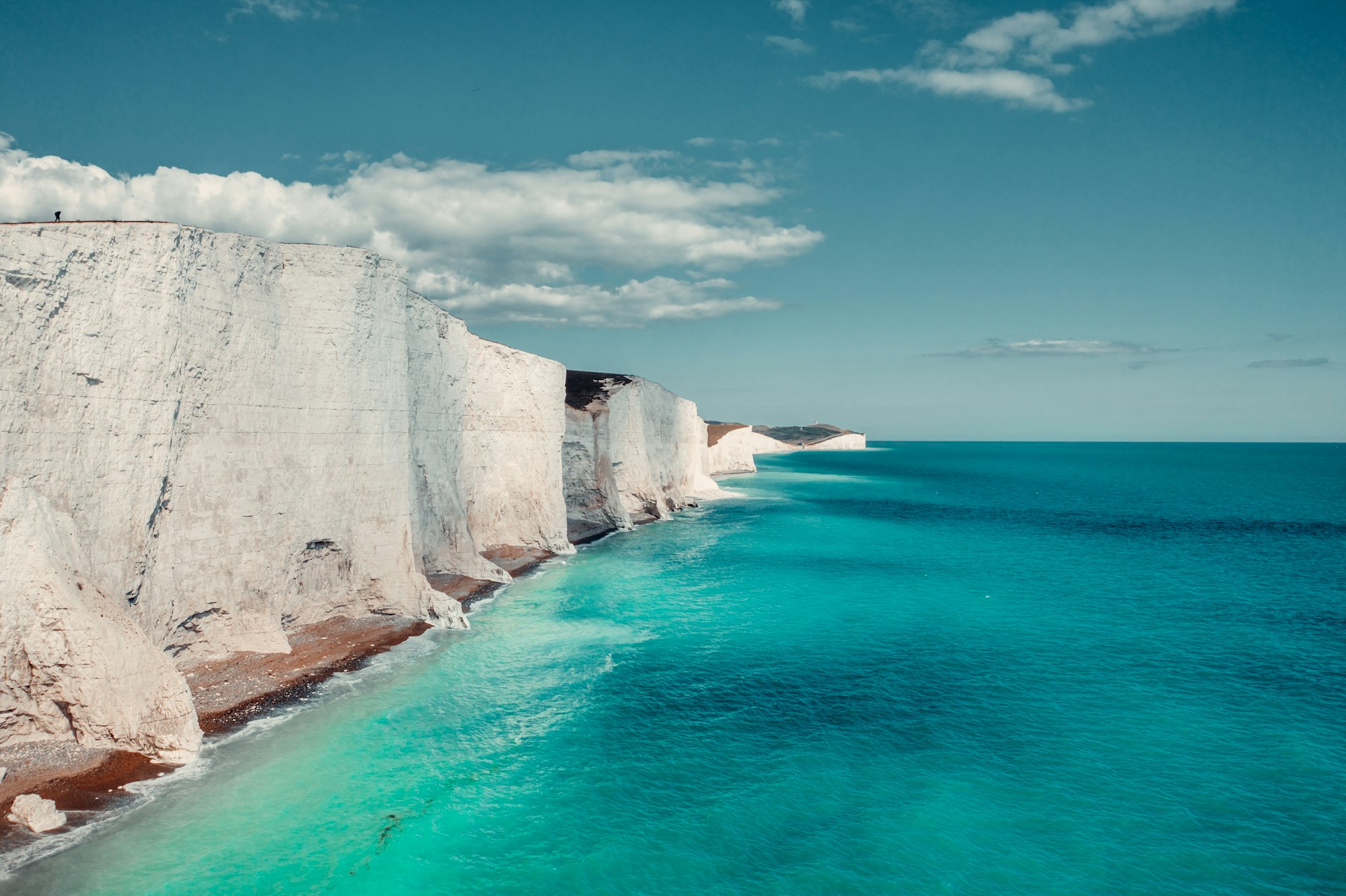 The white chalk cliffs of the Seven Sisters meeting a green-blue sea