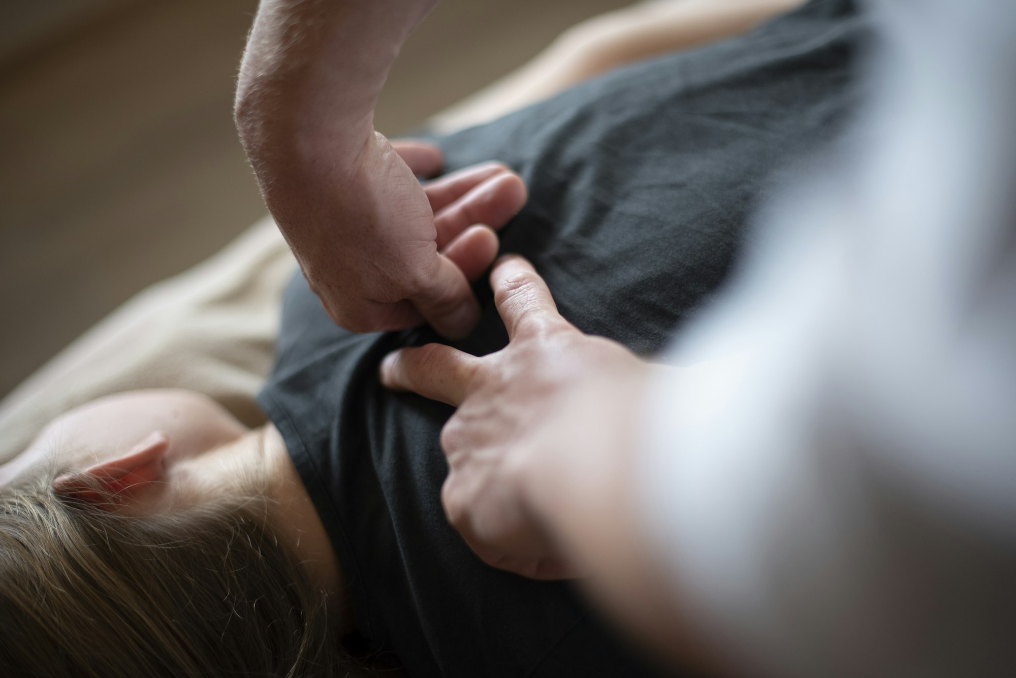 A therapist's hands working on a client's upper back